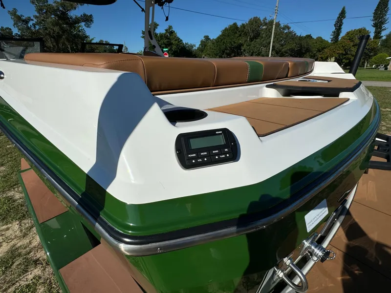 Slide: The Image of 2023 Axis A225 boat with green and white exterior, brown seating, and control panel. - 44
