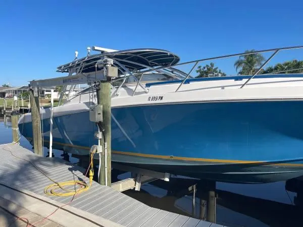 Slide: The Image of 2005 Fountain 38 LX boat docked, blue hull, sunny day, waterfront setting. - 0