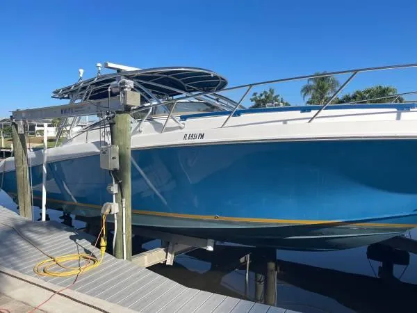 Slide: The Image of 2005 Fountain 38 LX boat docked, blue hull, sunny day, palm trees in background. - 16