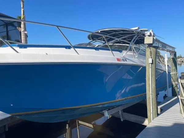 Slide: The Image of 2005 Fountain 38 LX boat in blue, docked on a lift under clear skies. - 2