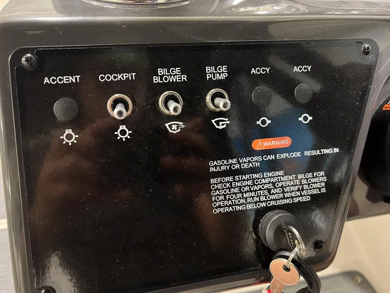 Slide: The Image of Control panel of a 2023 Bayliner VR5 Bowrider boat with various switches and warning label. - 16