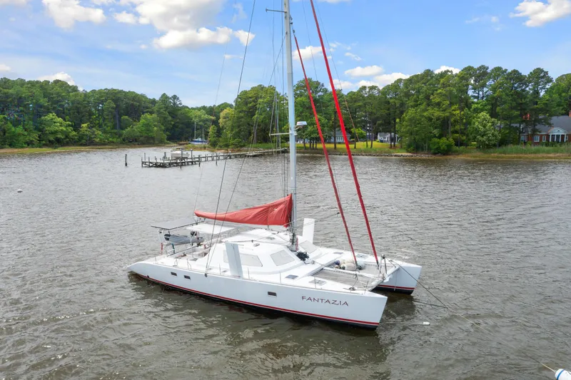 Slide: The Image of Switch 55 catamaran sailboat from 2006 named Fantazia anchored in a serene bay. - 0