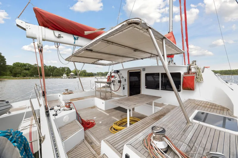 Slide: The Image of Deck of 2006 Switch 55 catamaran with red sail, docked on a calm river. - 16