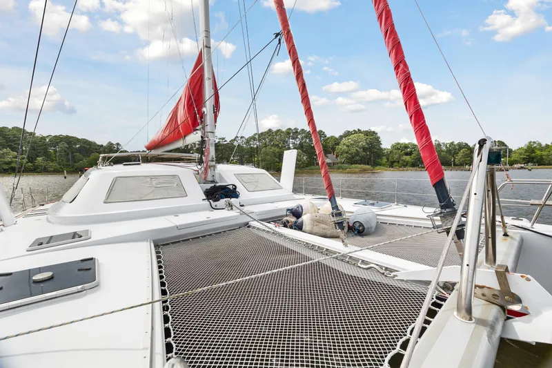 Slide: The Image of Catamaran sailboat Switch 55 (2006) with red sails docked on a calm river. - 25