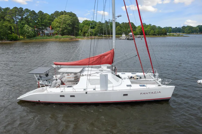 Slide: The Image of Catamaran sailboat Switch 55, 2006 model, named Fantazia, anchored on a serene lake. - 3