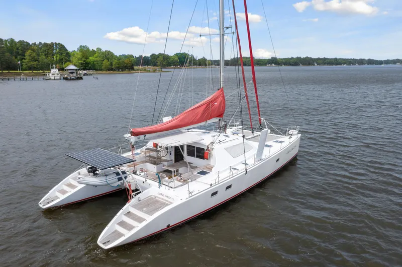 Slide: The Image of White 2006 Switch 55 catamaran with red sails on a calm lake. - 4
