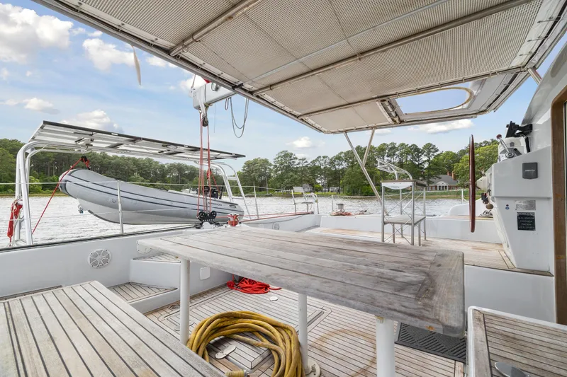 Slide: The Image of Outdoor deck of 2006 Switch 55 yacht with wooden table, benches, and docked dinghy. - 46