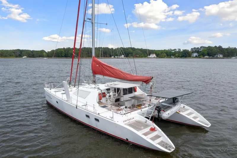 Slide: The Image of White Switch 55 catamaran sailboat with red sail on calm water, 2006 model. - 6