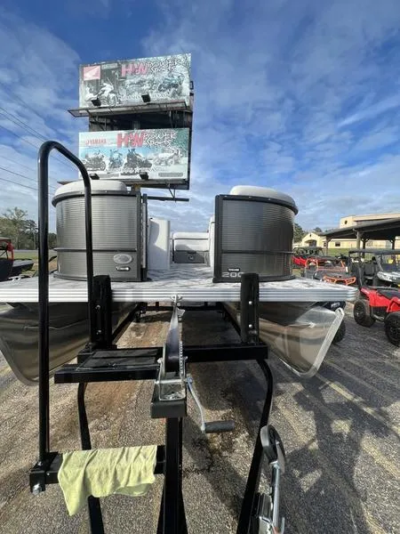 Slide: The Image of 2023 Crest Classic LX 200 L pontoon boat on trailer under blue sky. - 2