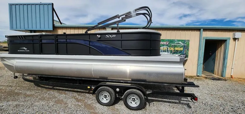 Slide: The Image of 2023 Bennington 23 SXSR pontoon boat on trailer, parked outside a building. - 18