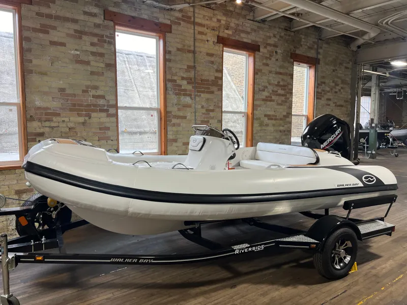 Slide: The Image of 2023 Walker Bay Generation 450 inflatable boat on trailer in indoor setting. - 0