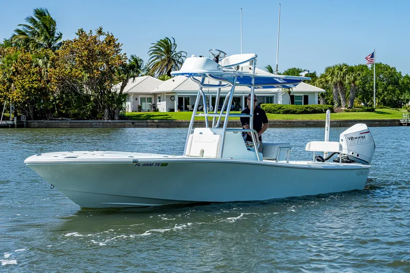 Slide: The Image of 2022 Conch Bay Boat on a serene waterway with lush greenery and a house in the background. - 15