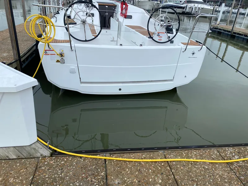 Slide: The Image of 2023 Jeanneau Sun Odyssey 380 docked, featuring dual steering wheels and a clean white hull. - 3