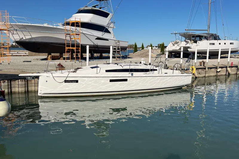 Slide: The Image of 2023 Jeanneau Sun Odyssey 380 sailboat docked at marina, clear blue sky, calm water. - 6