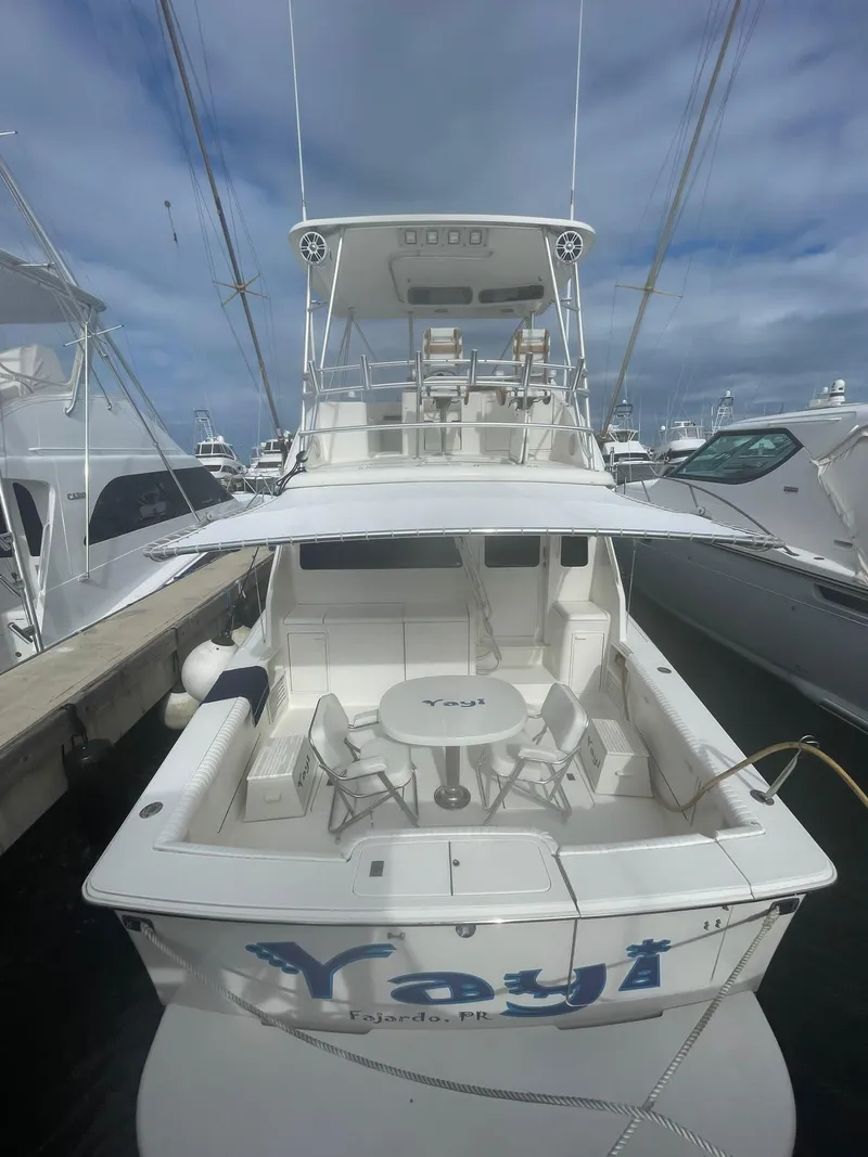 The Image of 2000 Ocean Yachts Convertible docked, featuring spacious deck and seating under a cloudy sky. - 0