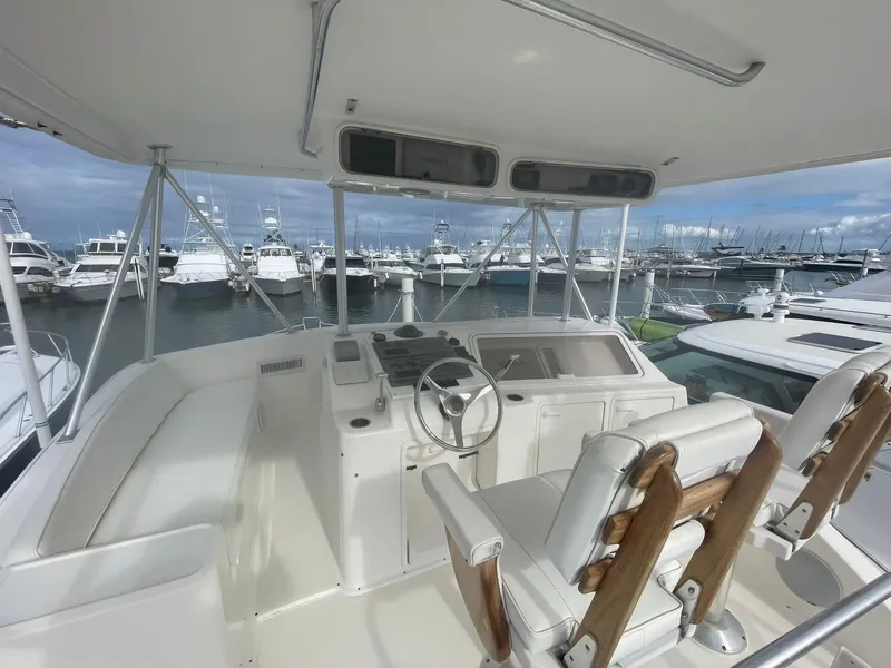 Slide: The Image of 2000 Ocean Yachts Convertible helm with marina view, featuring dual captain chairs and navigation controls. - 13