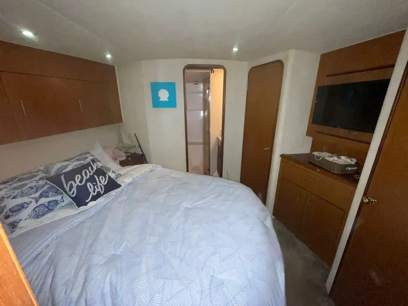 Slide: The Image of Bedroom interior of 2000 Ocean Yachts Convertible with cozy bed and wooden cabinetry. - 9