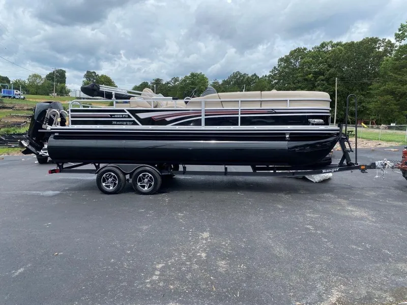 The Image of 2023 Ranger 223FC pontoon boat on a trailer, parked outdoors. - 0