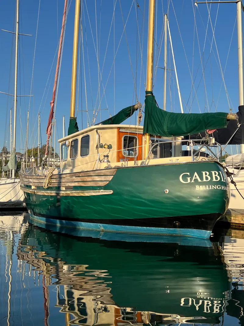 Slide: The Image of 1974 Fisher 37 sailboat docked in marina, green hull, wooden cabin, clear blue sky. - 4