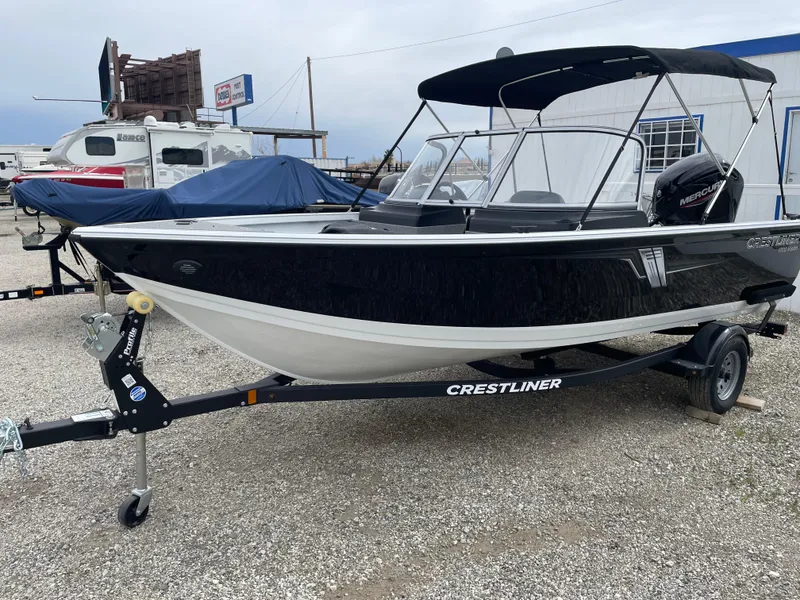 Slide: The Image of 2022 Crestliner 1700 Vision boat on trailer, black and white exterior, parked outdoors. - 0