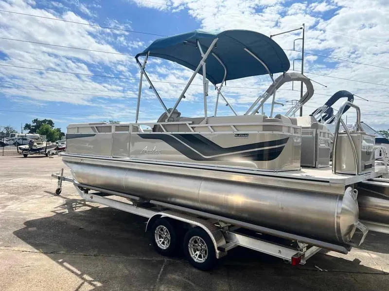 Slide: The Image of 2023 Avalon 2380 Venture Quad Lounger pontoon boat with blue canopy on trailer. - 3