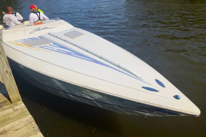 Slide: The Image of 1999 Baja 33 Outlaw speedboat docked on calm water, featuring sleek design and vibrant graphics. - 17