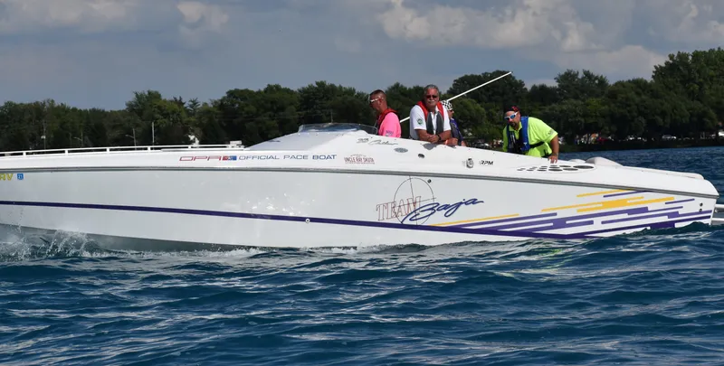 Slide: The Image of 1999 Baja 33 Outlaw speedboat cruising on water with passengers onboard. - 2