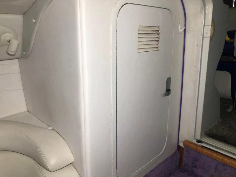 Slide: The Image of Interior cabin of a 1999 Baja 33 Outlaw boat with white seating and door. - 28