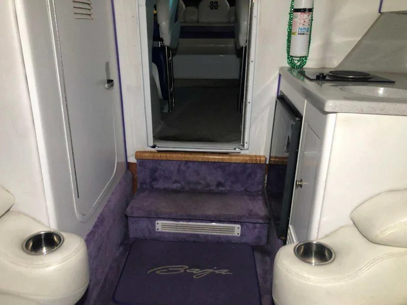 Slide: The Image of Interior of a 1999 Baja 33 Outlaw boat with purple carpet and white seating. - 29
