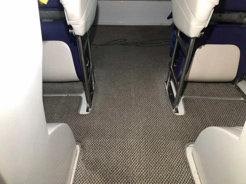 Slide: The Image of Interior view of a 1999 Baja 33 Outlaw boat, featuring carpeted flooring and white seating. - 30