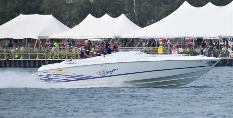 Slide: The Image of 1999 Baja 33 Outlaw speedboat cruising on water near tents and spectators. - 4