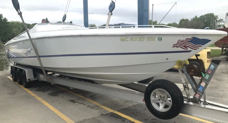 Slide: The Image of 1999 Baja 33 Outlaw boat on trailer with American flag decal, parked at marina. - 40
