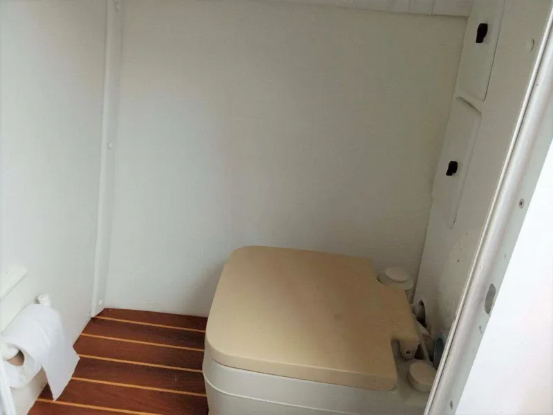 Slide: The Image of 1999 Baja 33 Outlaw boat interior with compact toilet and wooden flooring. - 9