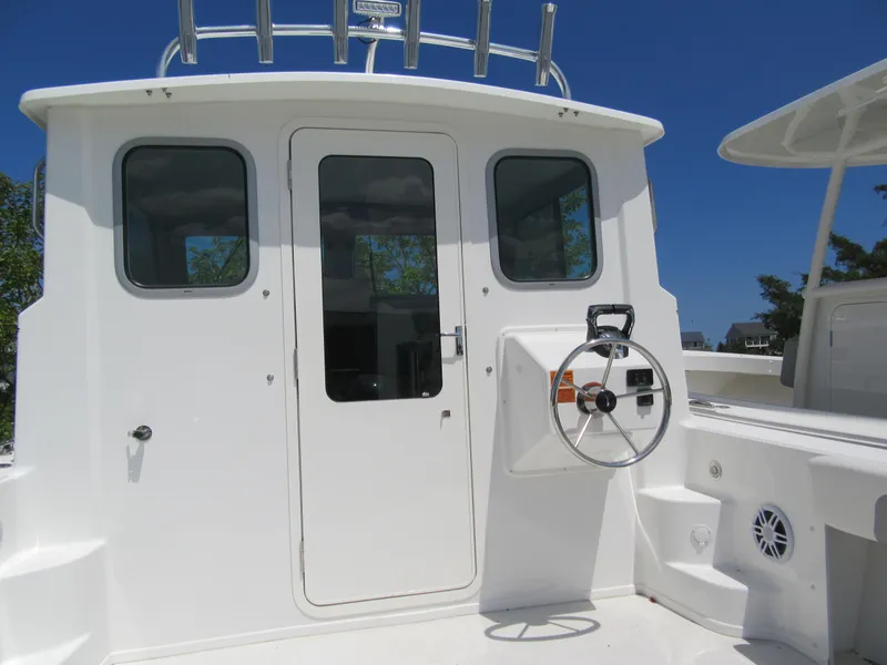 Slide: The Image of 2023 Parker 2520 XLD Sport Cabin boat exterior with steering wheel and cabin door. - 6