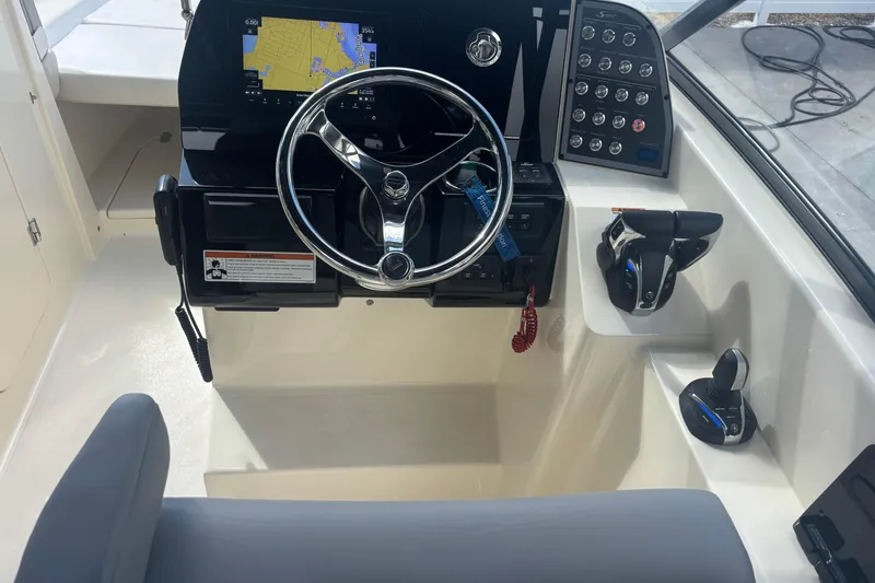 Slide: The Image of 2022 Scout 255 Dorado boat helm with steering wheel and navigation controls. - 17