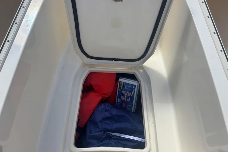 Slide: The Image of Open storage compartment on 2022 Scout 255 Dorado boat with life jackets and a first aid kit. - 24