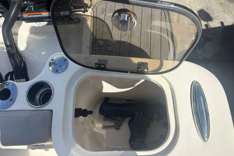 Slide: The Image of 2022 Scout 255 Dorado boat storage compartment with coiled hose and cup holders. - 30