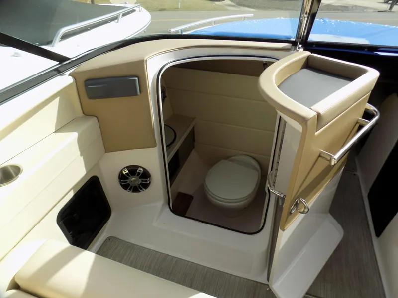 Slide: The Image of 2019 Regal 2800 Bowrider interior with compact marine toilet and beige seating. - 6