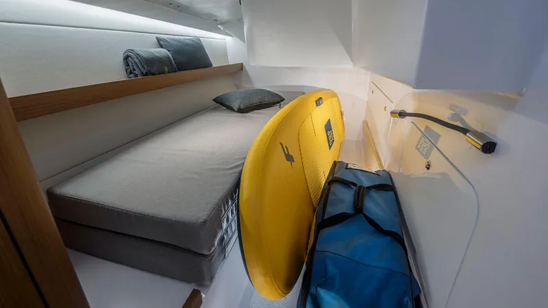 Slide: The Image of Beneteau First 36 (2024) cabin with bed, surfboard, and blue bag. - 11