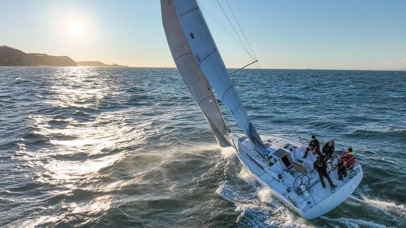 Slide: The Image of 2024 Beneteau First 36 sailboat navigating ocean waters at sunset. - 6