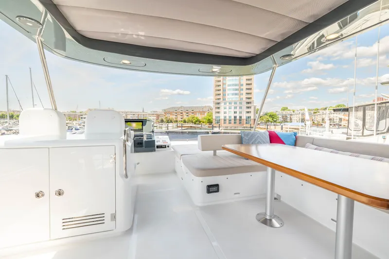 Slide: The Image of Sirena 58 yacht 2025 model, spacious deck with seating and table, marina view. - 26