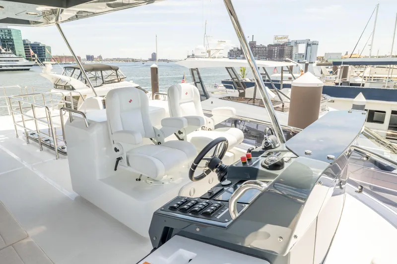 Slide: The Image of 2025 Sirena 58 yacht helm station with dual white captain chairs in marina. - 29