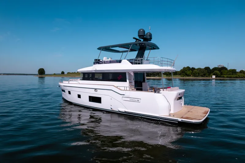 Slide: The Image of Luxury 2025 Sirena 58 yacht cruising on calm waters under a clear blue sky. - 6