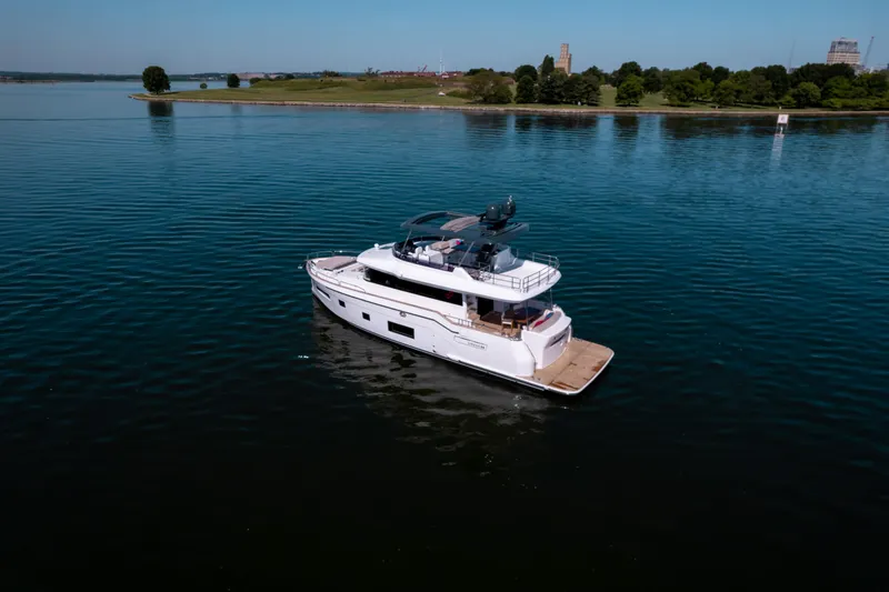 Slide: The Image of 2025 Sirena 58 yacht cruising on a calm lake with a scenic shoreline. - 7