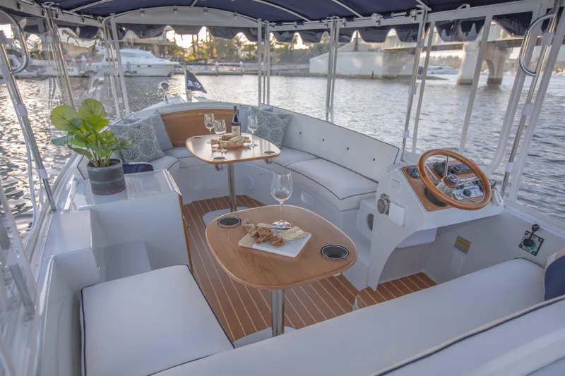 Slide: The Image of 2022 Duffy Snug Harbor 18 boat interior with seating, tables, and steering wheel. - 2