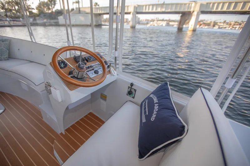 Slide: The Image of Duffy Snug Harbor 18 boat interior, 2022 model, with wooden steering wheel and waterfront view. - 4