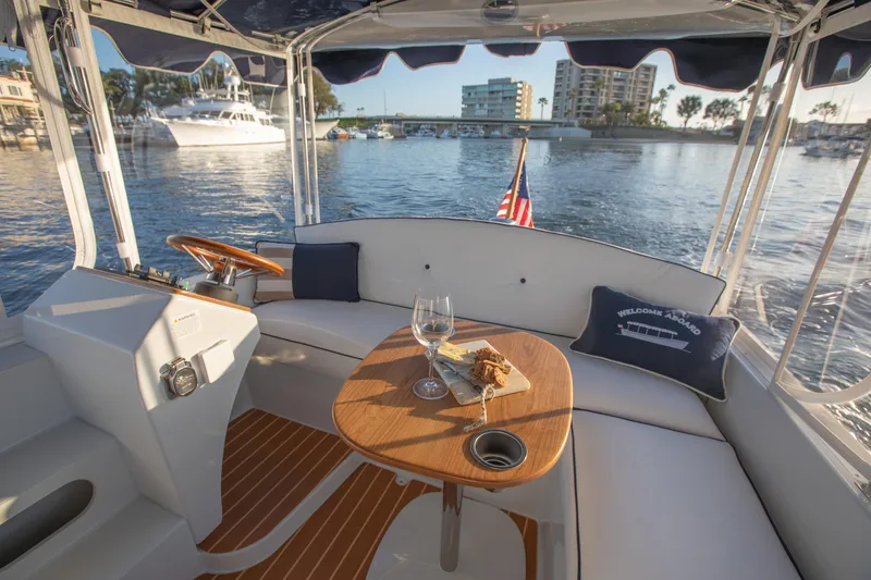 Slide: The Image of 2022 Duffy Snug Harbor 18 boat interior with table, wine glass, and waterfront view. - 8