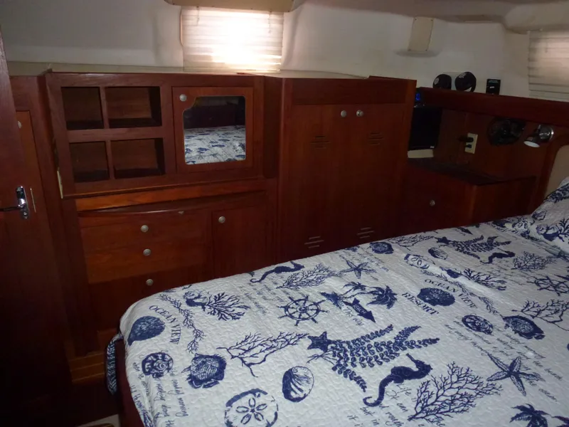 Slide: The Image of 2001 Hunter 420 Passage yacht interior with wooden cabinetry and nautical-themed bedding. - 35