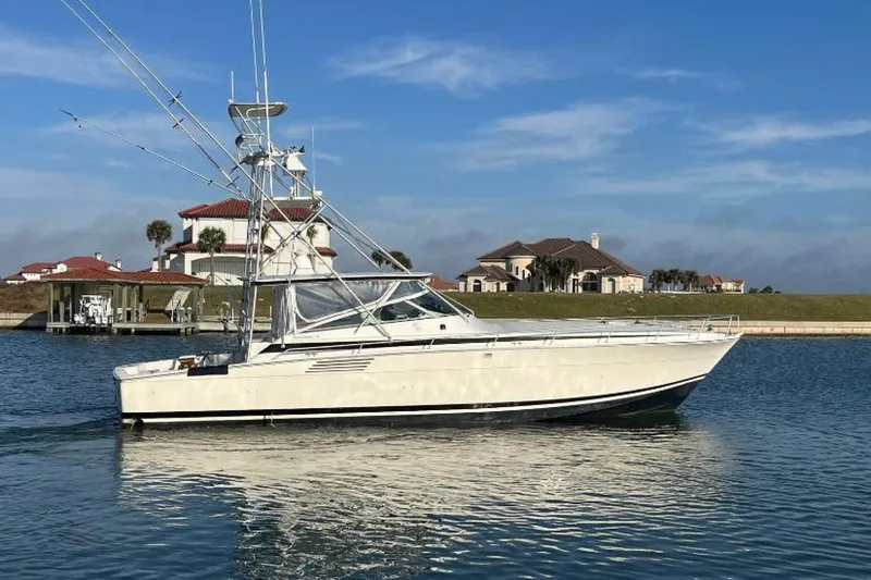 The Image of 1993 Bertram 46 Moppie yacht on calm water with houses in the background. - 1