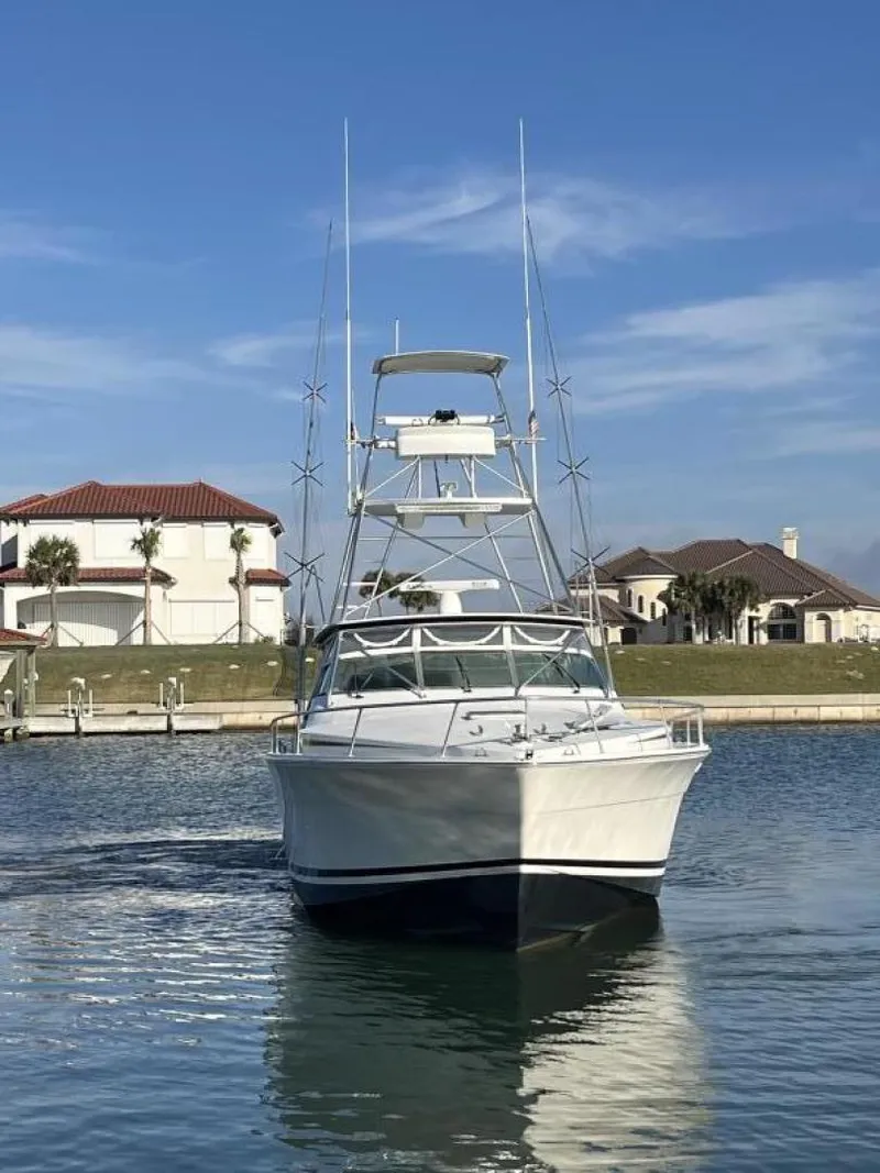 Slide: The Image of 1993 Bertram 46 Moppie yacht on calm water near luxury homes. - 21